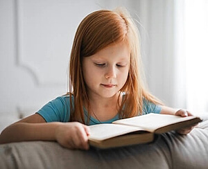 Mädchen liest konzentriert in einem Buch – Lernen für Kinder in Bern mit ruhiger, individueller Unterstützung.