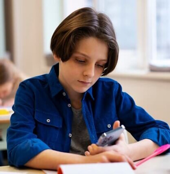 Sekundarschüler sitzt konzentriert am Pult und rechnet mit dem Taschenrechner – fokussiertes Arbeiten innerhalb der Lernstufen.