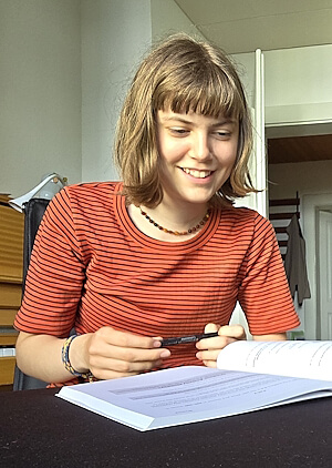 Motivierte Gymnasiastin erweitert konzentriert ihr Französisch‑Vokabular während der Nachhilfe Französisch; sie arbeitet aufmerksam mit Heft und Lernmaterialien.