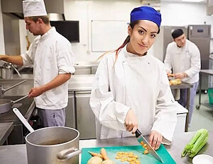 Berufsfachschülerin in der Ausbildung zur Köchin EFZ schneidet in einer Küche Zwiebeln für eine Suppe, Bild für die Nachhilfe Berufsfachschule.