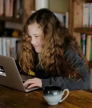 Sekundarschülerin arbeitet konzentriert am Laptop und schreibt einen Text in der Nachhilfe Sekundarschule.