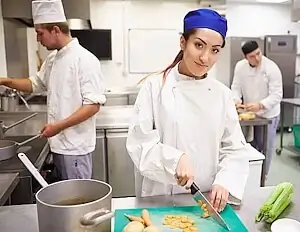 Berufsfachschülerin in der Ausbildung zur Köchin EFZ schneidet in einer Küche Zwiebeln für eine Suppe, Bild für die Nachhilfe Berufsfachschule.